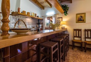 A kitchen with a wooden bar, bar stools, a sink, and a window with curtains. - Country Home "Can Moreno" with Pool, A/C, Wi-Fi, Garden & Terrace (Illes Balears)