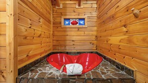 Eine Sauna mit Holzwänden, einer herzförmigen Sitzbank und einem Steinboden.