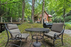 Un chalet rustique doté d’une terrasse, entouré d’une forêt.