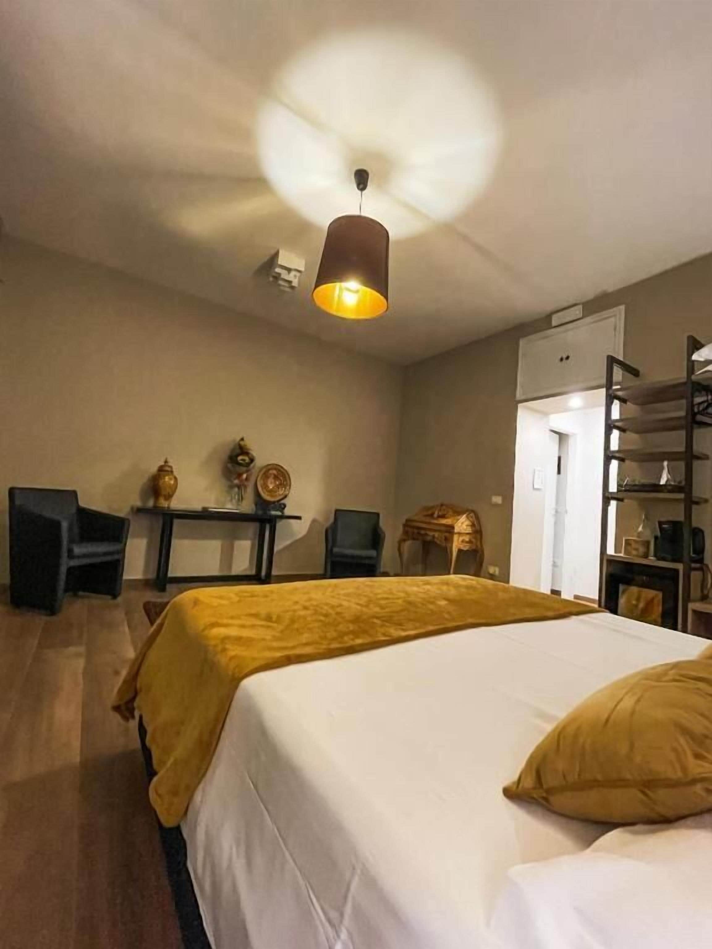 Una camera d'albergo con un letto, una scrivania, una sedia e una libreria.