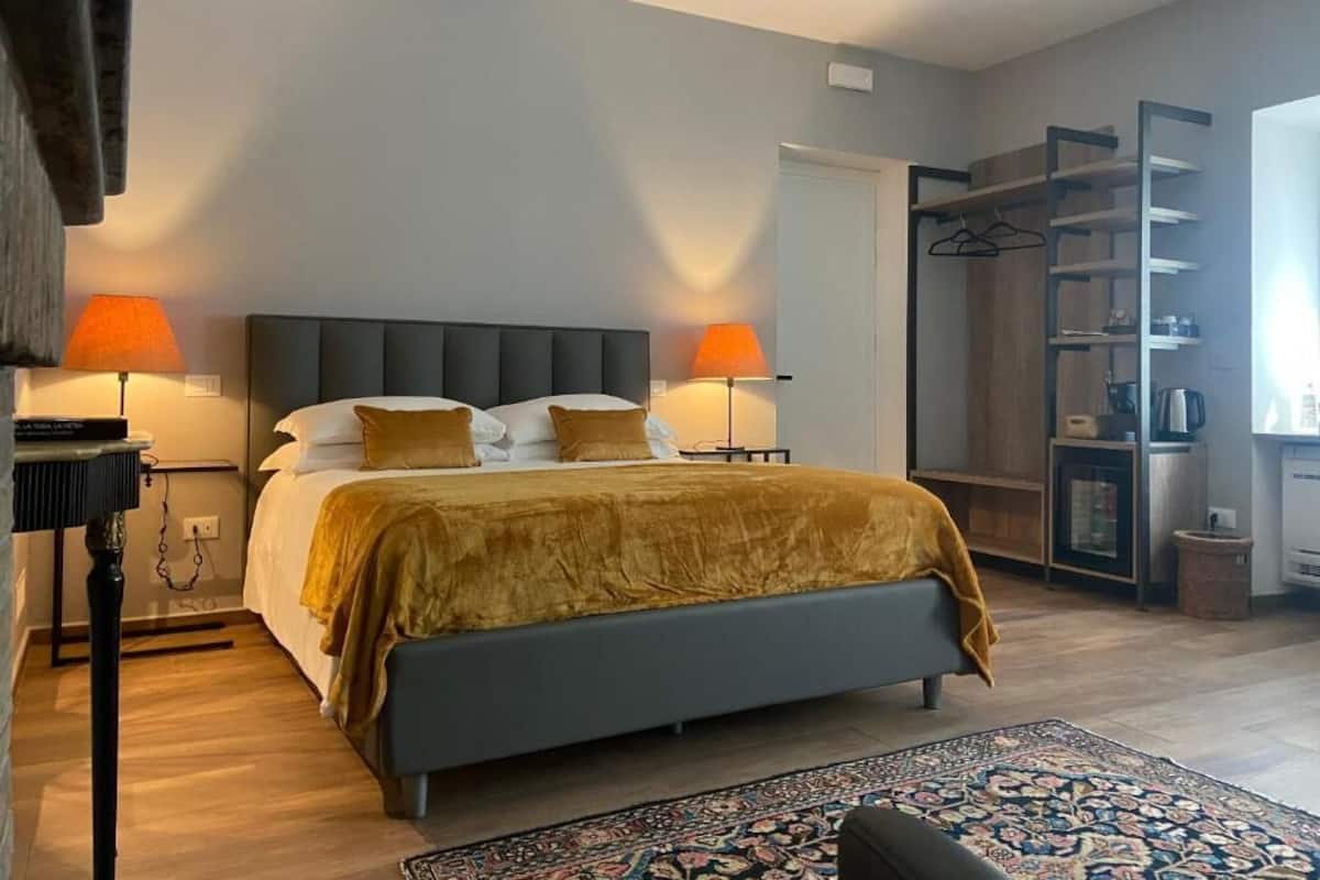 A modern bedroom with a bed, bedside lamps, a wardrobe, and a small table.