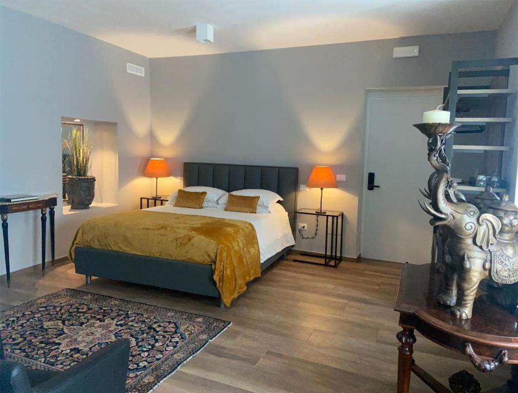 Ein Schlafzimmer mit einem Bett, zwei Nachttischlampen, einem Nachttisch, einer dekorativen Statue und einem Holzboden.