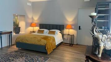 Ein Schlafzimmer mit einem Bett, zwei Nachttischlampen, einem Nachttisch, einer dekorativen Statue und einem Holzboden.
