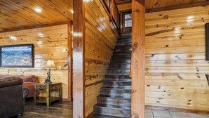 A wooden staircase in a log cabin interior with a couch and lamp in the foreground. - Spacious*Private Pool*Home Theater*Close to Pigeon Forge (PIGEON FORGE)