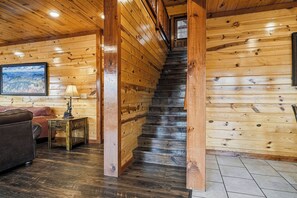 A wooden staircase in a log cabin interior with a couch and lamp in the foreground. - Spacious*Private Pool*Home Theater*Close to Pigeon Forge (PIGEON FORGE)