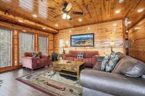 A wooden interior with a ceiling fan, two sofas, a coffee table, and a large window with blinds. - Spacious*Private Pool*Home Theater*Close to Pigeon Forge (PIGEON FORGE)