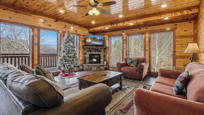 A cozy cabin interior with a fireplace, leather sofas, a wooden coffee table, and a Christmas tree. - Spacious*Private Pool*Home Theater*Close to Pigeon Forge (PIGEON FORGE)