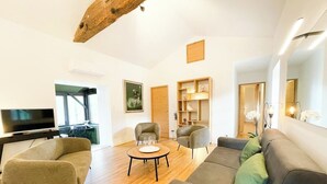 Een moderne woonkamer met een bank, fauteuils, een salontafel en een televisie.