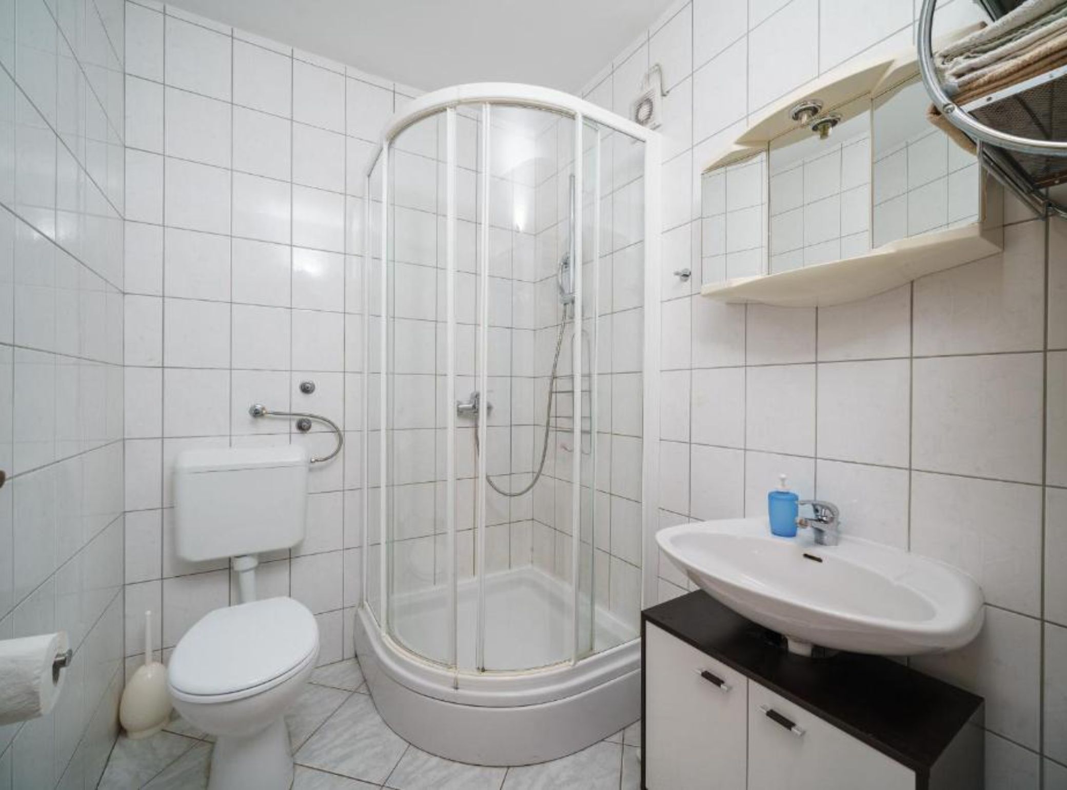 A bathroom with a glass-enclosed shower, a toilet, a sink, and a towel rack.