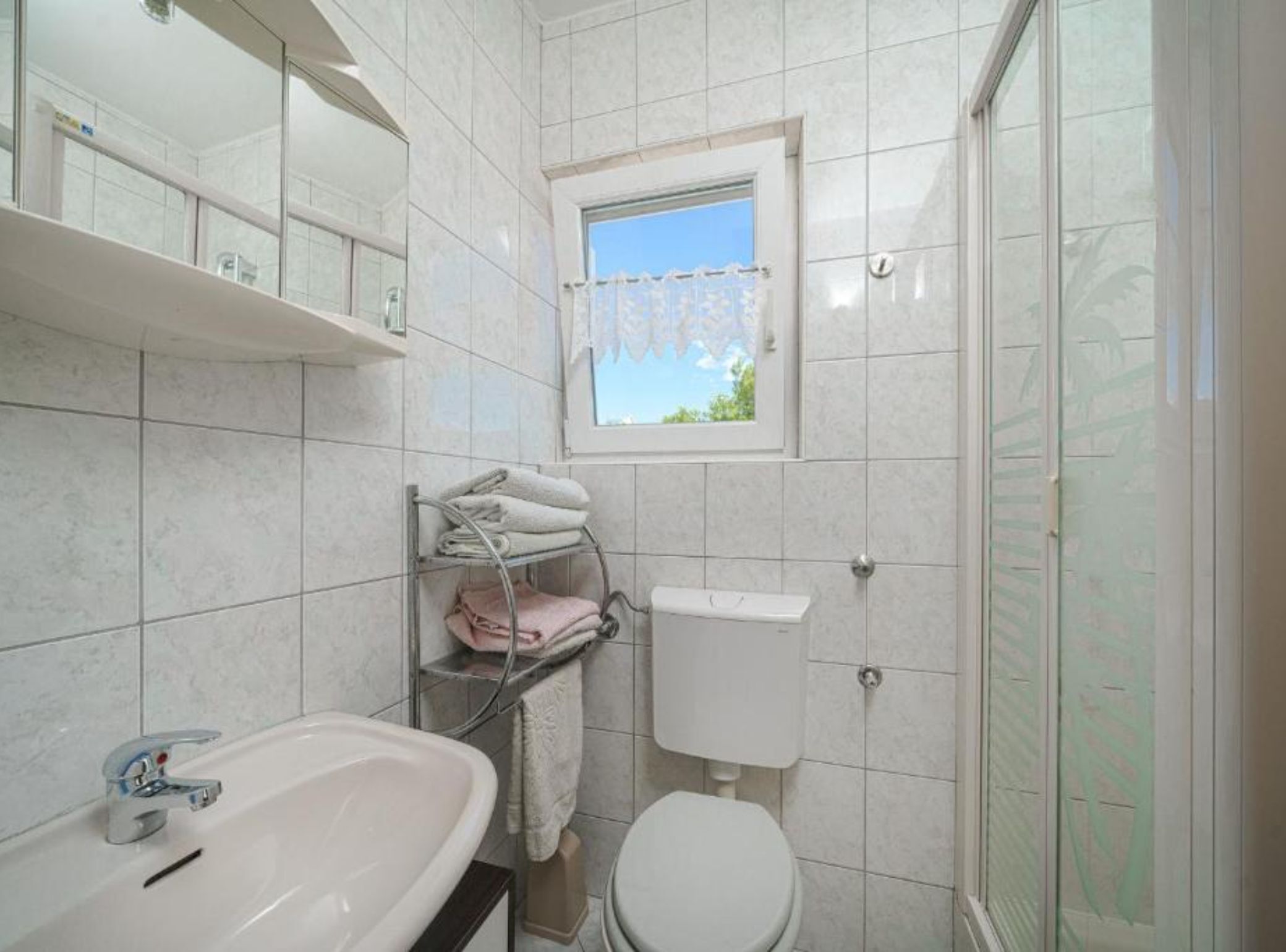 Un baño con lavamanos, inodoro y ventana.