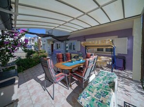 A covered patio with a table and chairs, a sofa, and a window with blinds. - Apartments Milka Vodice (Vodice)