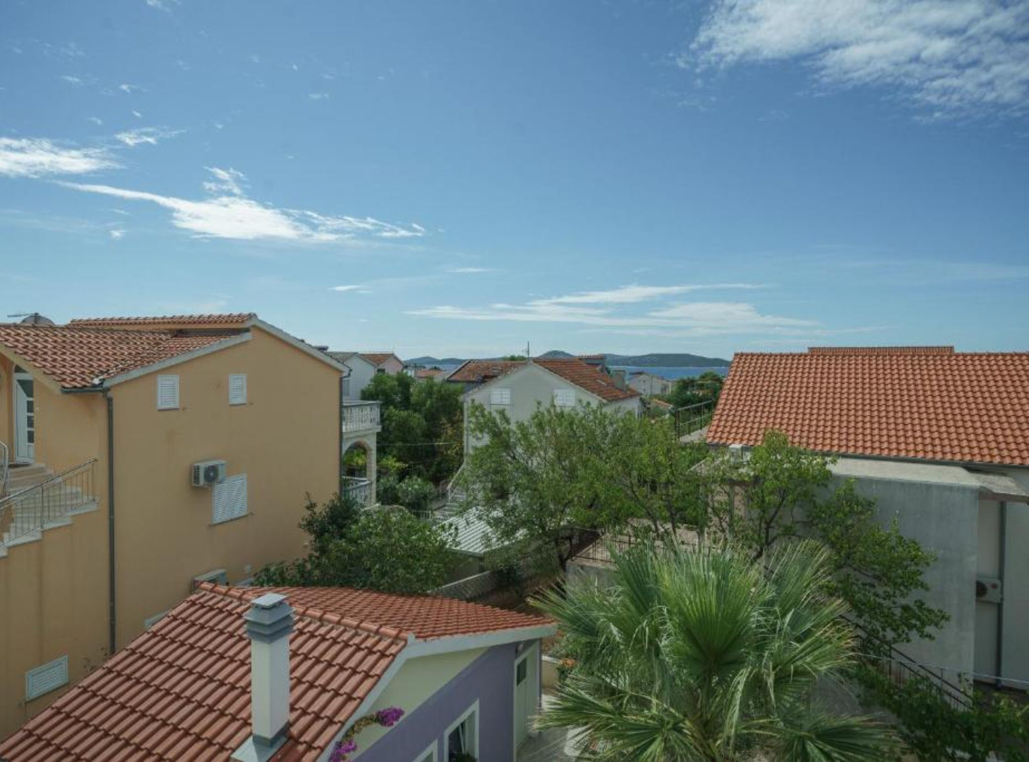 Un quartier résidentiel avec des toits recouverts de tuiles en terre cuite, un ciel dégagé et de la verdure.