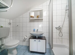 A bathroom with a toilet, sink, mirror, shower, and a cabinet. - Apartments Milka Vodice (Vodice)