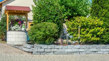 A garden area with a stone wall, a gazebo, and various plants.