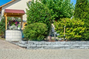 A garden area with a stone wall, a gazebo, and various plants. - Apartment 'Hopfengarten 4' with Shared Terrace, Shared Garden and Wi-Fi (Spalt)