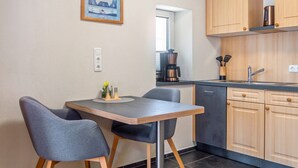 A compact kitchen with a dining area, wooden cabinets, a coffee maker, and a framed picture on the wall. - Apartment 'Hopfengarten 4' with Shared Terrace, Shared Garden and Wi-Fi (Spalt)