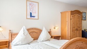 A neatly made bed with a wooden headboard, two bedside tables with lamps, and a wooden wardrobe. - Apartment 'Hopfengarten 4' with Shared Terrace, Shared Garden and Wi-Fi (Spalt)