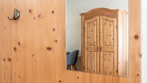 A wooden wardrobe with a mirror, a chair, and a door with a brass handle. - Apartment 'Hopfengarten 4' with Shared Terrace, Shared Garden and Wi-Fi (Spalt)