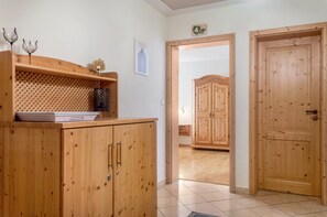 Un mueble de madera con repisa celosada, una puerta con manija y un suelo de baldosas.