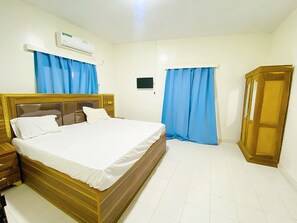Un dormitorio con cama, armario, aire acondicionado y cortinas.