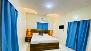 A bedroom with a bed, bedside tables, curtains, an air conditioning unit, and a ceiling light. - Hôtel SangaCity Bakel  (Bakel)