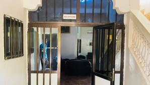 A reception area with a sign, a staircase, and a bed in the background. - Hôtel SangaCity Bakel  (Bakel)