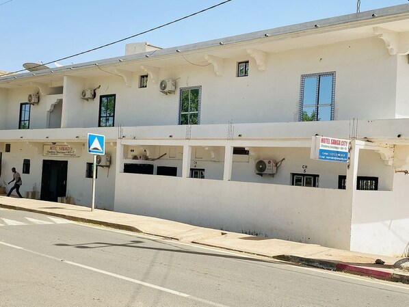 Un edificio de varios pisos con un letrero que dice 'HOTEL SANGA CITY' y una señal azul direccional.