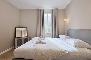 Una camera da letto con un letto, un comodino, uno specchio e una finestra con tende.