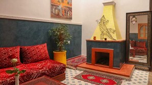 A room with a sofa, a fireplace, a mirror, and a painting on the wall. - Riad Seven Doors  (Marrakech)