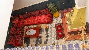 A room with a sofa set, a small table, a decorative rug, a potted plant, and a wall with a patterned design. - Riad Seven Doors  (Marrakech)