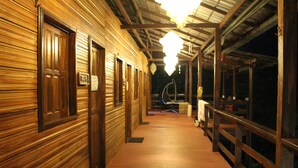 Un couloir en bois, avec des portes, un banc et un luminaire suspendu.