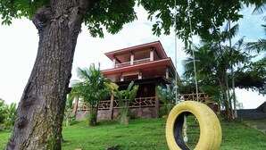 Un bâtiment doté d’un balcon, entouré d’arbres et bordé d’une pelouse.