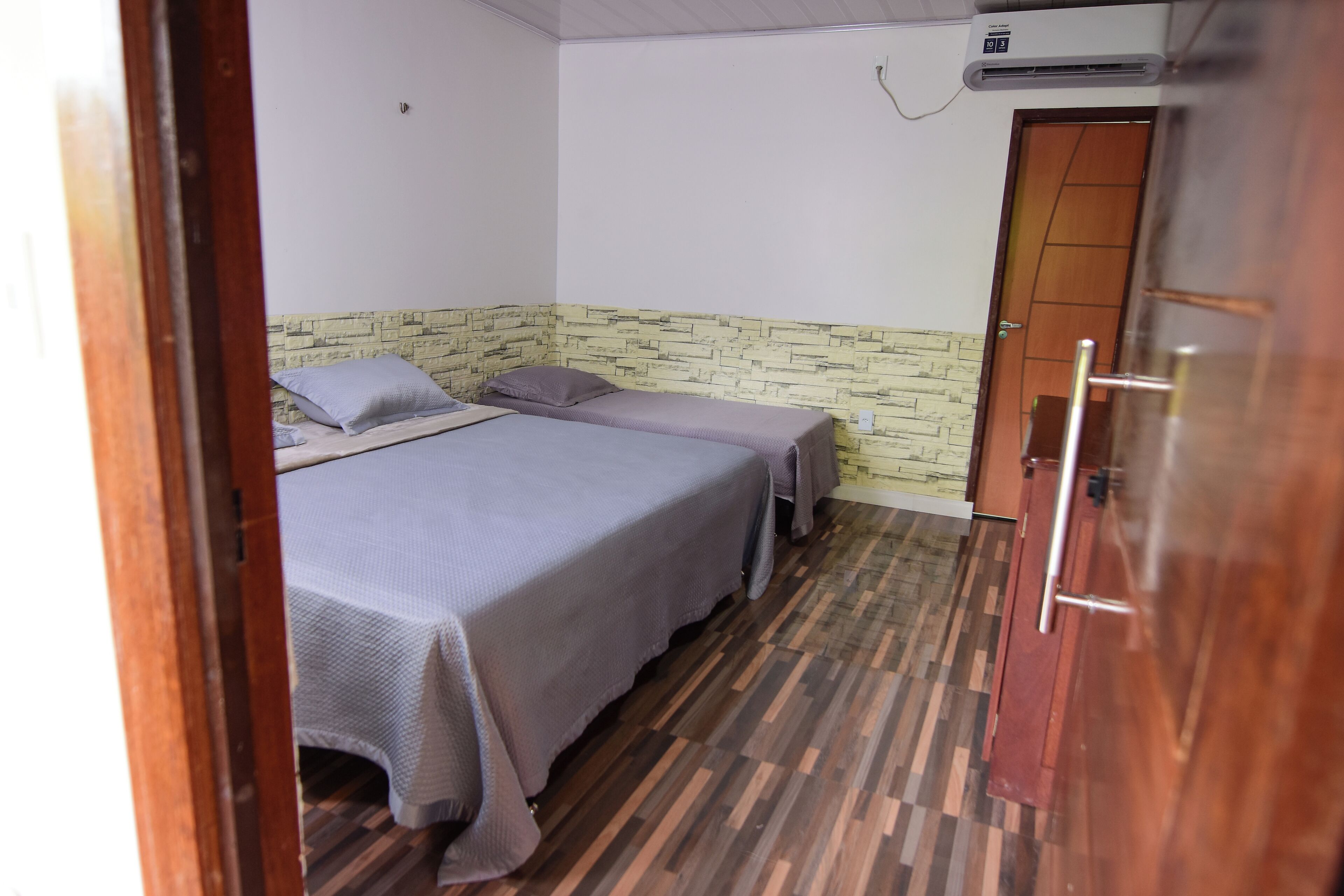A room with two beds, a wooden wardrobe, and a door with a handle.