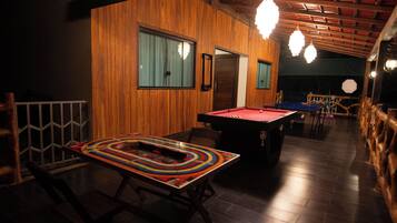 A billiards table in a dimly lit room with wooden walls and a sloped ceiling.