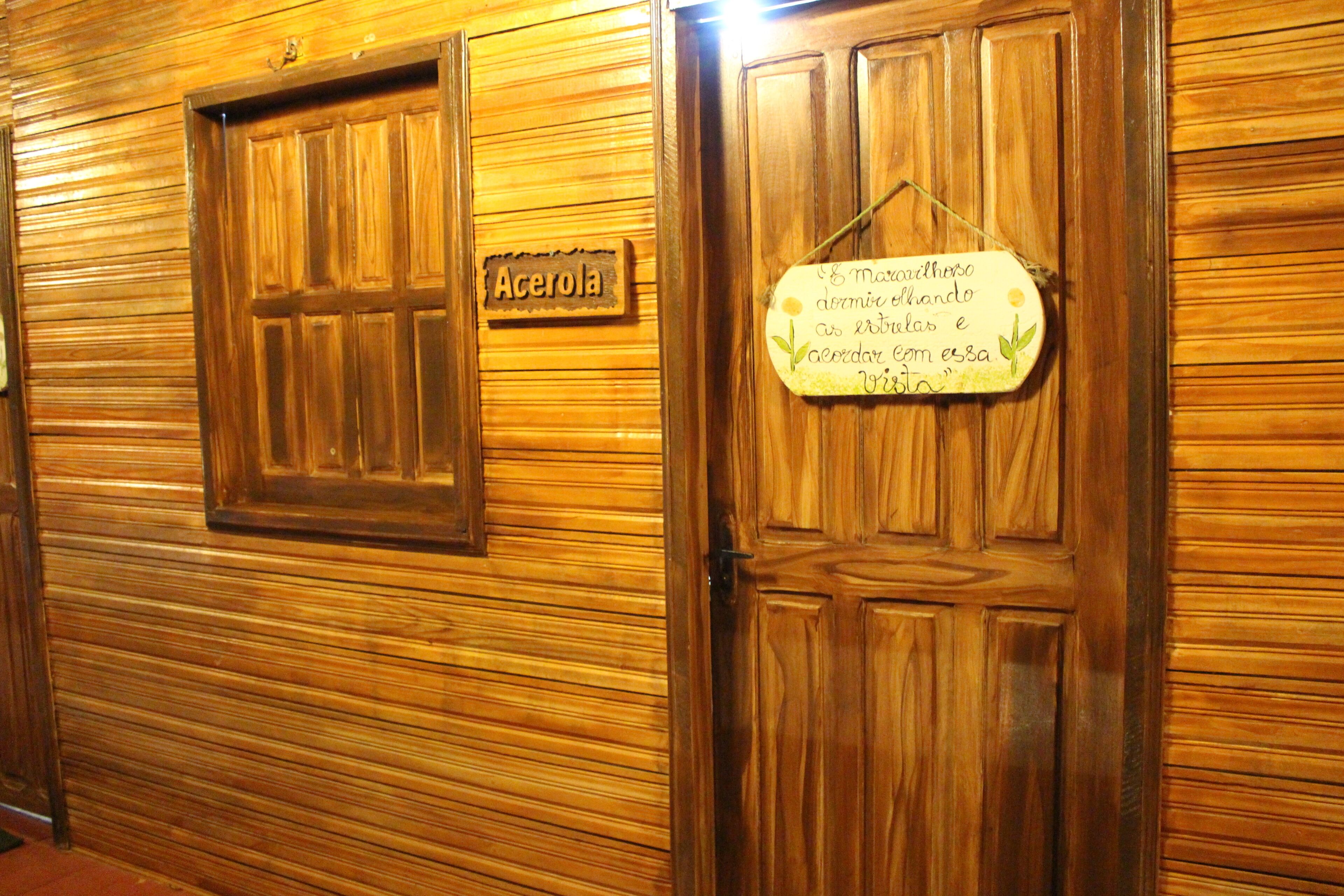Des portes en bois, l’une portant une enseigne avec le mot « Acerola », et l’autre affichant un message en portugais.