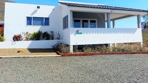 A modern two-story house with a covered porch, a small garden, and a clear blue sky. - Villa Aloë - Ocean view villa with pool in Lagun (Lagun)