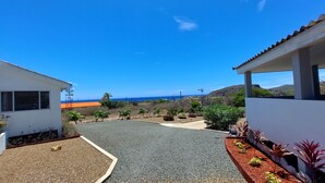 A residential area with a paved driveway, a windmill, and a view of the ocean. - Villa Aloë - Ocean view villa with pool in Lagun (Lagun)