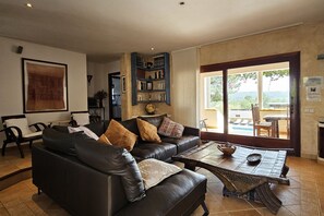 En stue med sofa, sofabord, bogreol og store vinduer.