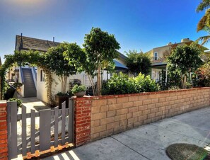 A residential area with houses, a brick wall, and a wooden gate. - 313 E Bay A | Cozy Bay Cottage near Balboa Village (Newport Beach)