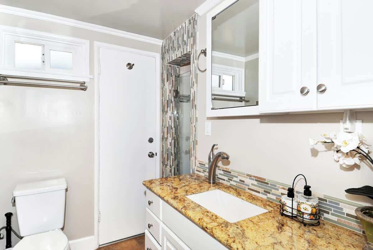 Une salle de bain équipée de toilettes, d’un lavabo, d’un miroir et de placards.