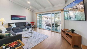 A modern living room with a sofa, coffee table, and a TV. - Spacious Duplex with Patio and Deck, Steps to Newport Beach (Newport Beach)