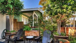En terrasse med to Adirondack-stole, et lille rundt bord og en træbænk.
