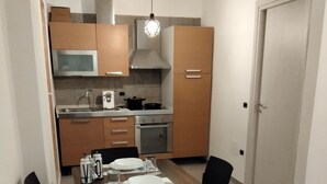 Una cocina compacta con electrodomésticos modernos, una mesa de comedor lista para cuatro personas y una puerta a la derecha.