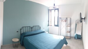 Un dormitorio con cama, una mesita auxiliar redonda, un armario y un espejo.