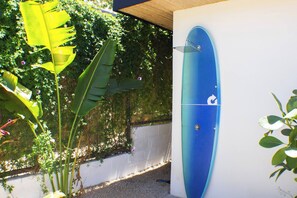 A blue surfboard mounted on a wall, surrounded by greenery and a white wall. - Golden Shore Villa in Tamarindo (Tamarindo)