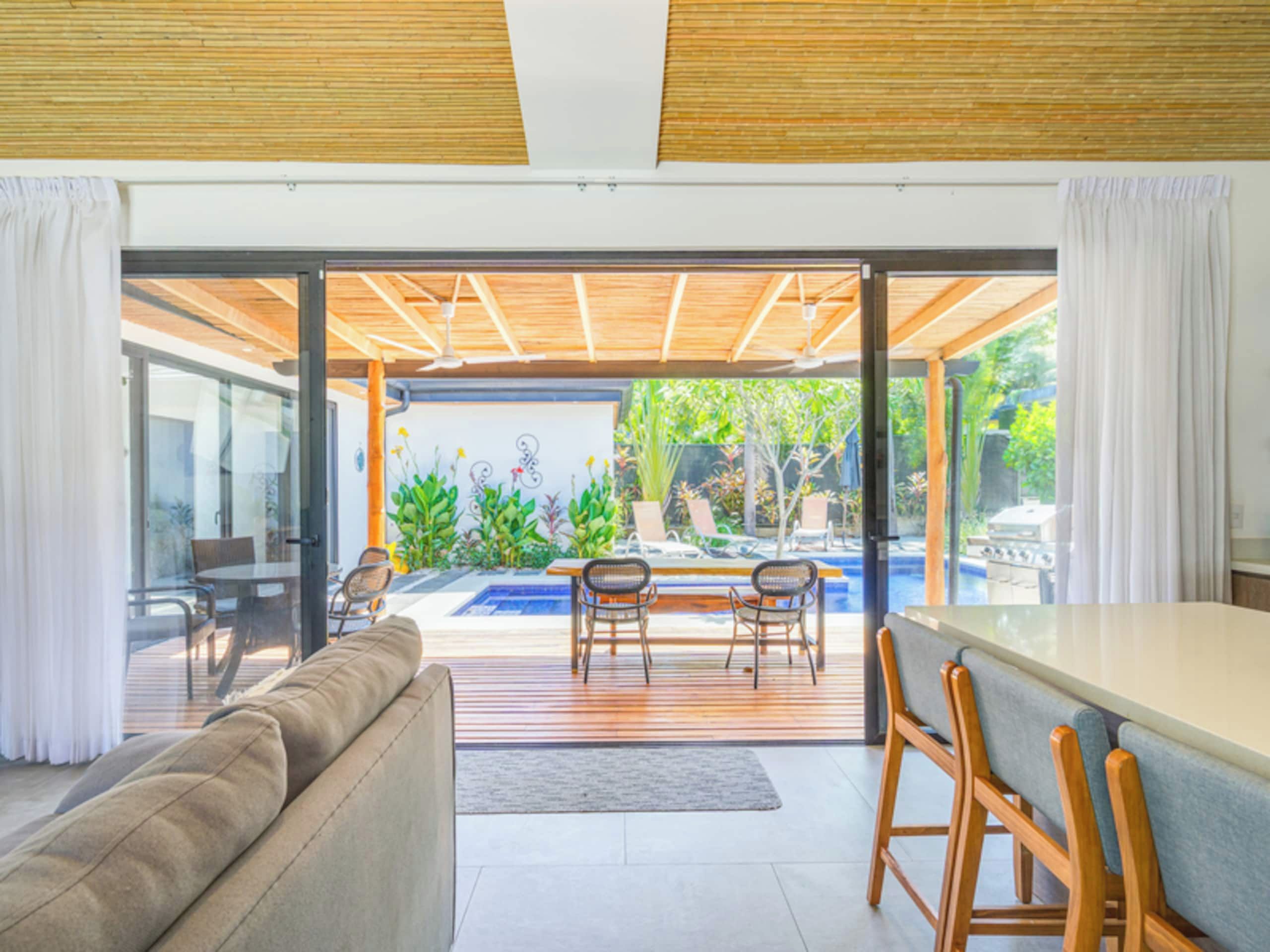 A modern interior with a glass door leading to an outdoor area featuring a pool and lounge chairs.