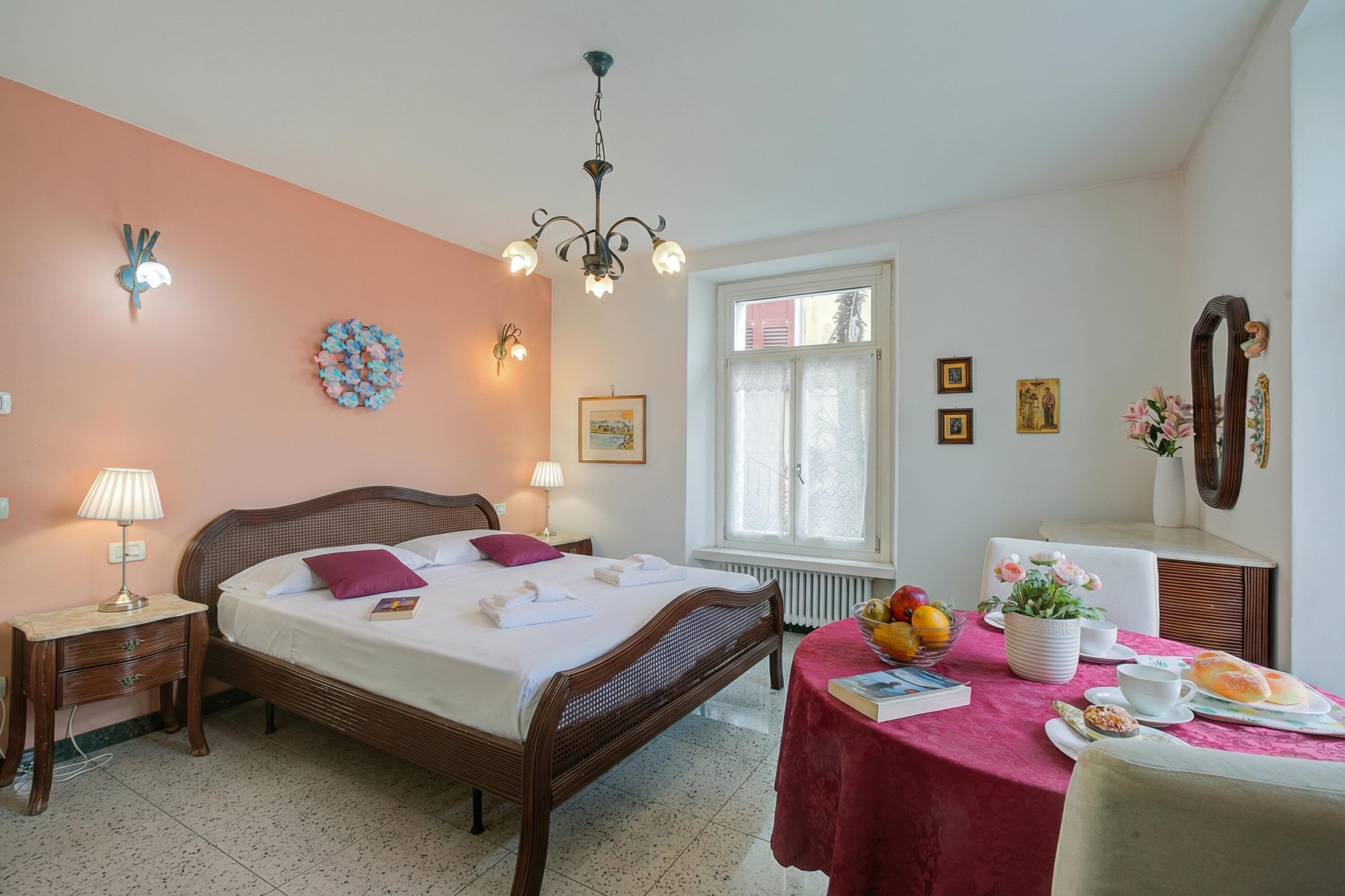 Une chambre d’hôtel comprenant un lit, des tables de chevet, une fenêtre, une table où le petit-déjeuner est servi, et un miroir.