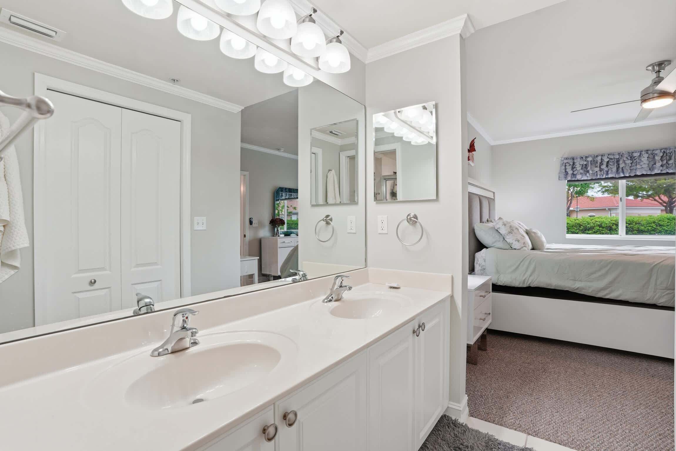 A bathroom with a double sink, large mirrors, and a ceiling fan.
