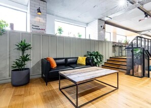 A modern interior with a black leather sofa, a wooden coffee table, and potted plants. - Student Only Modern Studio at Portobello Near Kensington and Chelsea (London)