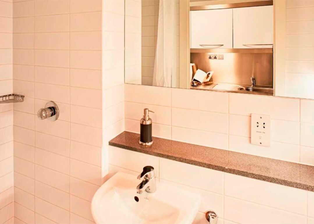 A bathroom with a sink, mirror, and shower area.